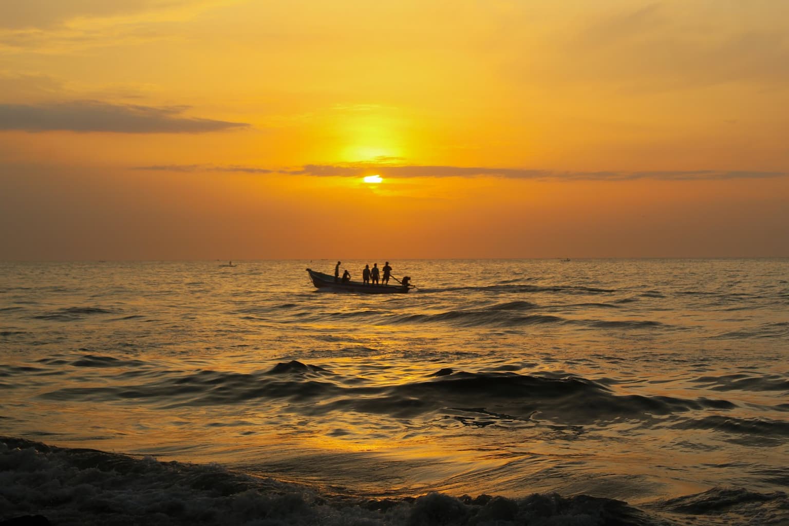 A small fishing boat on golden water at sunrise