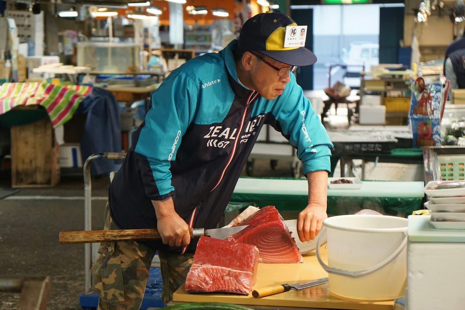 A fishmonger cutting a deep red tuna loin