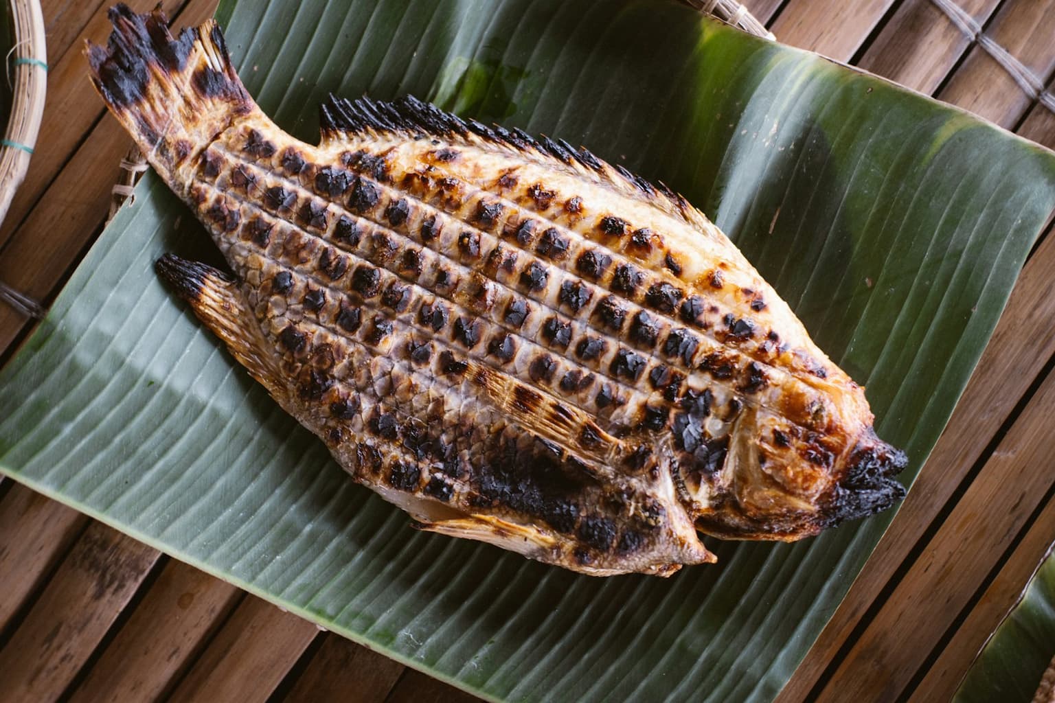 A grilled whole fish served on a banana leaf